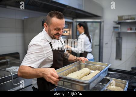 Chef and cook working on their dishes indoors in restaurant kitchen. Stock Photo