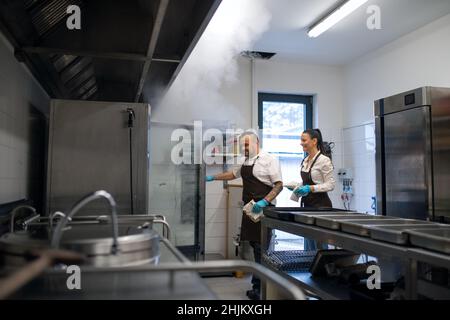 Chef and cook working on their dishes indoors in restaurant kitchen. Stock Photo