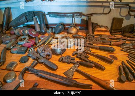 A variety of vintage tools laying on the workbench from rusty pipe wrenches with an assortment of tape measures and other miscellaneous old tools Stock Photo