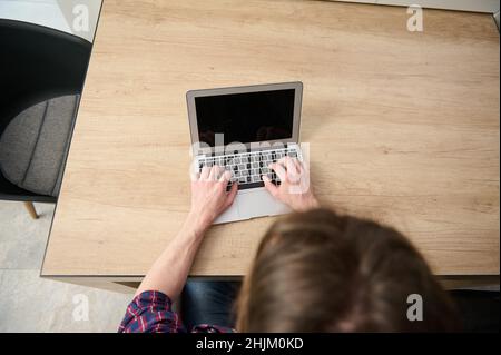 Overhead view of a business person, businessman, entrepreneur, journalist copywriter freelancer developer working remotely on laptop, typing text on l Stock Photo