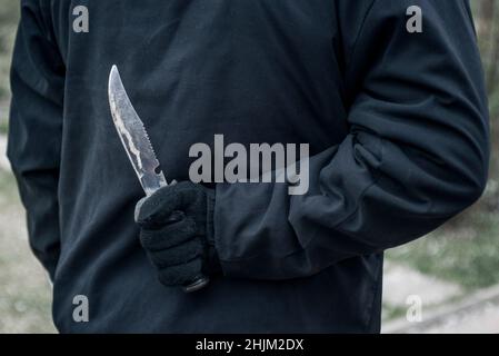 Man with the knife behind his back. Man holding sharp knife behind his back. Stock Photo