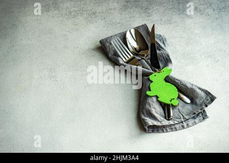 Minimalistic table setting with grey napkin and cutlery decorated with wooden bunny Stock Photo