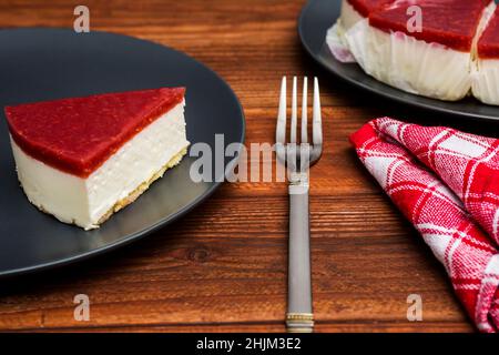 Classical cheesecake with raspberry jelly on rustic wood table background. Stock Photo