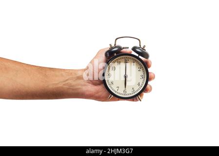 Man is holding black alarm clock in one hand on white background. Stock Photo