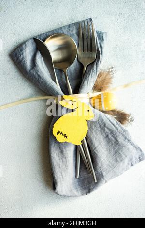 Minimalistic table setting with grey napkin and cutlery decorated with wooden bunny Stock Photo