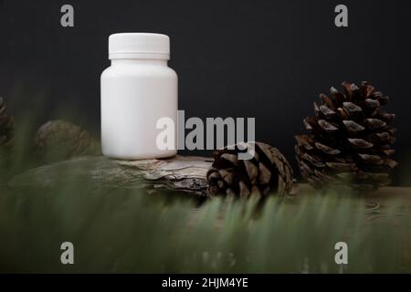 Mockup of a white plastic jar on a black background with tree bark and spruce branches, beauty product packaging. Stock Photo