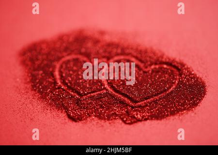Red table with two hearts, finger painted on glitter. Stock Photo