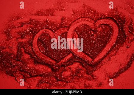 Red table with two hearts, painted by finger on glitter, top view Stock Photo