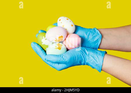 Hands in blue medical gloves holding painted easter eggs. Easter time in quarantine concept. Concept of Easter holyday during epidemy of coronavirus. Stock Photo