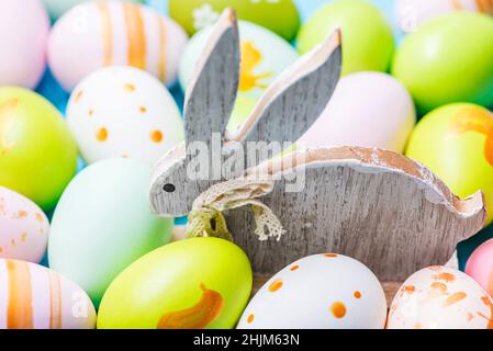 Colorful Easter eggs and wooden rabbit. Cute rabbit among Easter eggs. Stock Photo