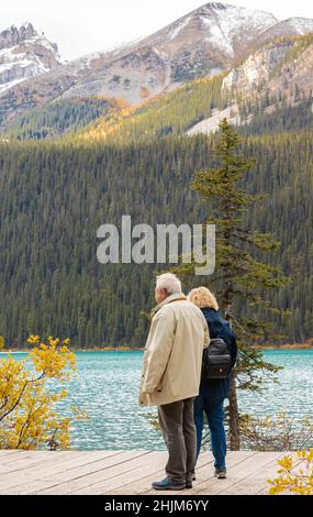 Elderly couple pensioners enjoying the view at Louise Lake in Banff National Park, Canadian Rockies, Alberta, Canada. Stock Photo