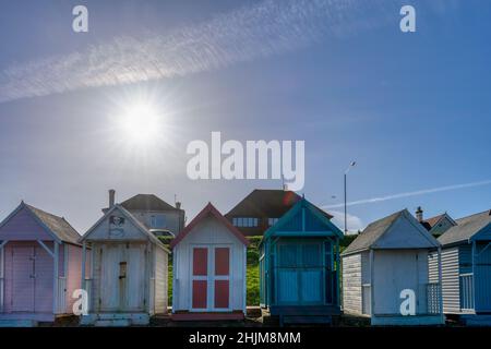 A row of English traditional beach huts, painted in vibrant pastel colours at Herne Bay seen on a sunny Sunday morning in January. Stock Photo