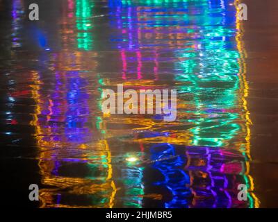 Reflection on the Wet Floor of Colored Lights on a Dark Background Stock Photo