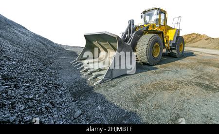 Wheel loader beside a pile of crushed gravel, cut out on white background Stock Photo