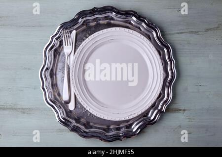 White plate with cutlery on a vintage shiny metal tray Stock Photo