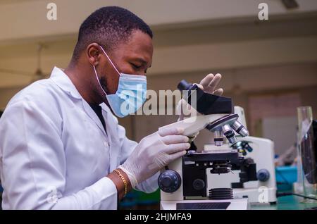young scientist looking through a microscope in a laboratory. Young scientist doing some research. Stock Photo