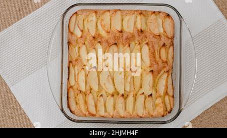 Fresh baked apple cake with biscuit base close up on kitchen table, just from the oven, flat lay