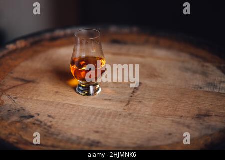 Glencairn glass with whiskey on bourbon barrel Stock Photo