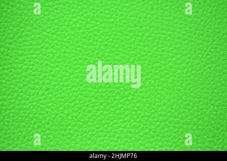 Fragment of genuine leather with a fine mesh pattern artificially dyed in bright green close-up. Background, pattern, texture. Stock Photo