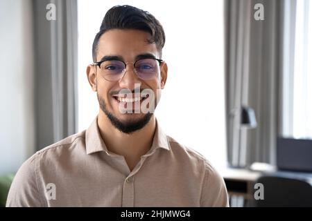 Headshot of smiling handsome hindu man looking at camera standing at home Stock Photo