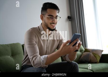 Young man using phone and internet technology sitting on sofa rest at home Stock Photo
