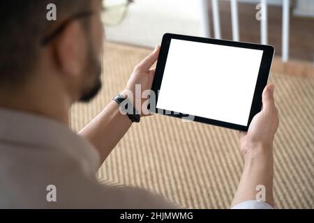 Closeup of Indian man holding digital tablet sitting on sofa at home office Stock Photo