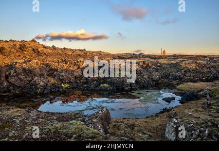 Rugged Lava fields in Iceland.Hopsnes Lighthouse can be seen on the horizon. Stock Photo