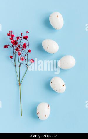Easter minimal composition with eggs and flowers on the blue background. Easter concept. Vertical photo, flat lay. Stock Photo