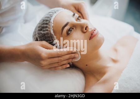 Closeup portrait of a cosmetician's hands washing and cleaning the client's face preparing for peeling procedure. Facial skin treatment. Closeup Stock Photo