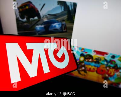 Mobile phone with logo of Swedish company Modern Times Group AB (MTG) on screen in front of business website. Focus on center of phone display. Stock Photo