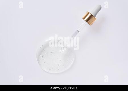 Liquid serum and dropper on a white background. Frontal view. Serum drops from a pipette. Stock Photo