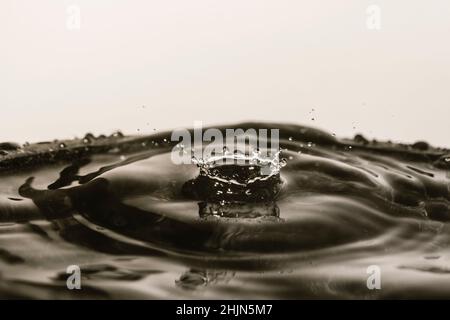 Drops of water falling on smooth wet surface. Blurred background. Stock Photo