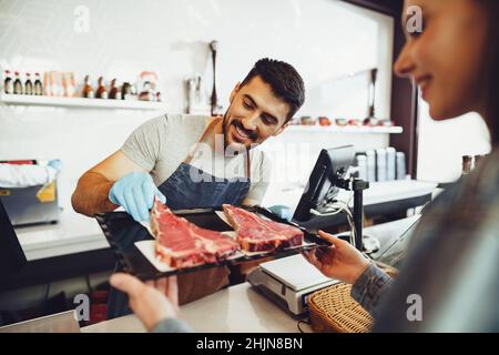 Butcher's shop seller helps to choose product to woman customer Stock Photo