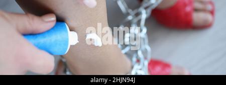 Woman applies cream to legs tied with chain closeup Stock Photo
