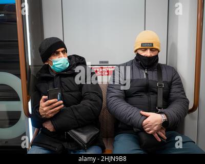 Moscow. Russia. January 26, 2022. Two men in protective masks are sitting in a subway car. Selective focus.