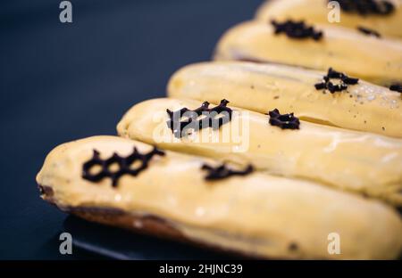 Close-up of eclairs in yellow glaze on a black background. Stock Photo
