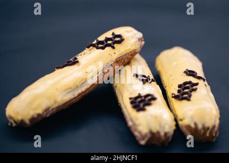 Close-up of eclairs in yellow glaze on a black background. Stock Photo