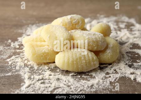 Raw potato gnocchi with flour on wooden background Stock Photo