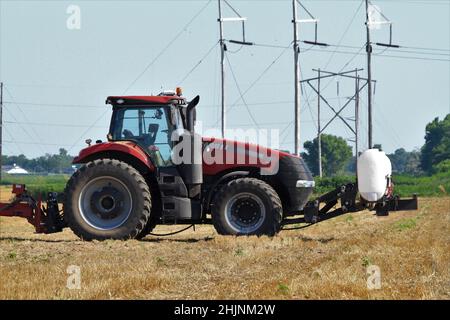 A Case International farm tractor in a farm field with spray equipment on the back with blue sky in Kansas out in the country. Stock Photo