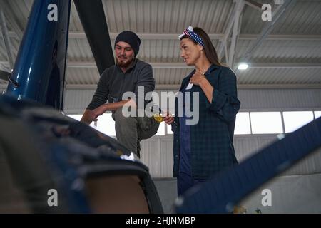 Two engineers using special tools while analyzing details of copter in hangar Stock Photo