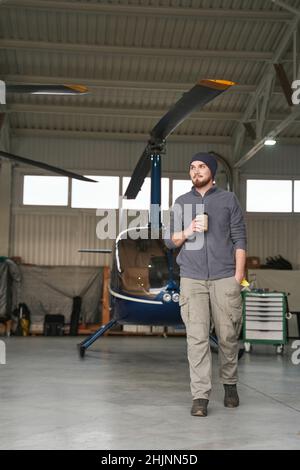 Bearded male walking in garage with copter Stock Photo