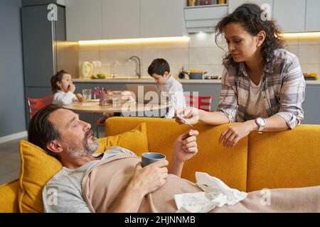 Wife checking her husband temperature on thermometer Stock Photo