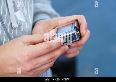 A man holds in his hands and looks through the footage on an action camera Stock Photo