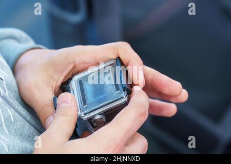 A man holds in his hands and looks through the footage on an action camera Stock Photo