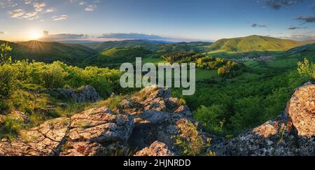mountain meadow in morning light. countryside springtime landscape with valley in fog behind the forest on the grassy hill. fluffy clouds on a bright Stock Photo