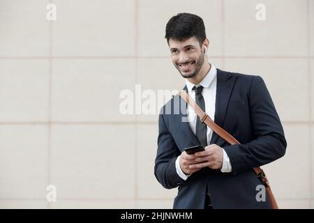 Portrait of smiling young entrepreneur wearing earbuds when calling coworker Stock Photo