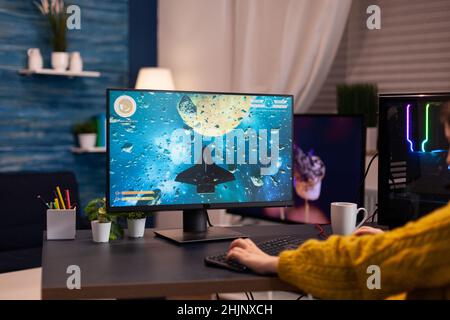 Closeup of gamer player woman playing space shooter videogames during online championship using RGB powerful computer in streaming studio. Gaming concept at home. Esport competition Stock Photo
