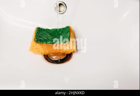 Yellow sponge for dishes under water Stock Photo