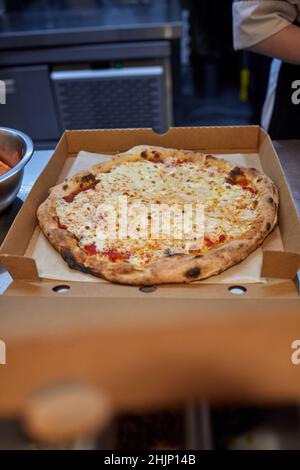 Pizza in a cardboard box against a dark background. Space for text. Pizza delivery Stock Photo