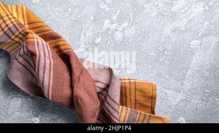 Top view of brown folded kitchen towel or serviette on grey concrete background Stock Photo